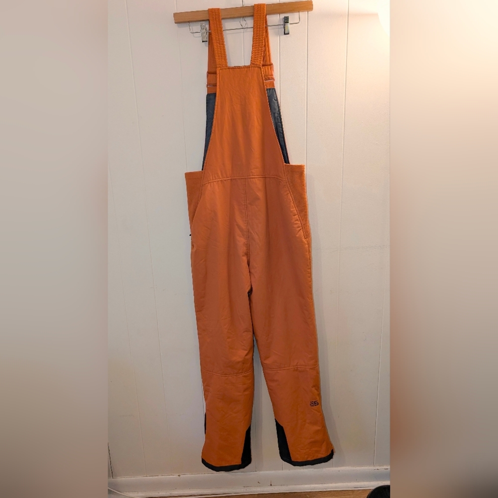 Zermatt insulated snow bibs in a bold orange color.